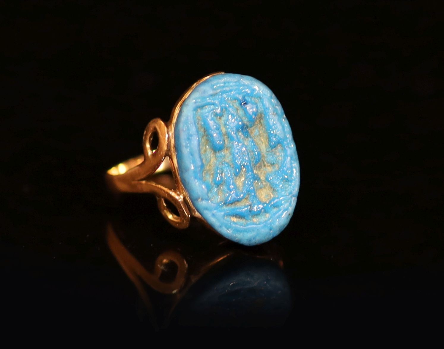 An antique gold and oval turquoise glazed intaglio set ring